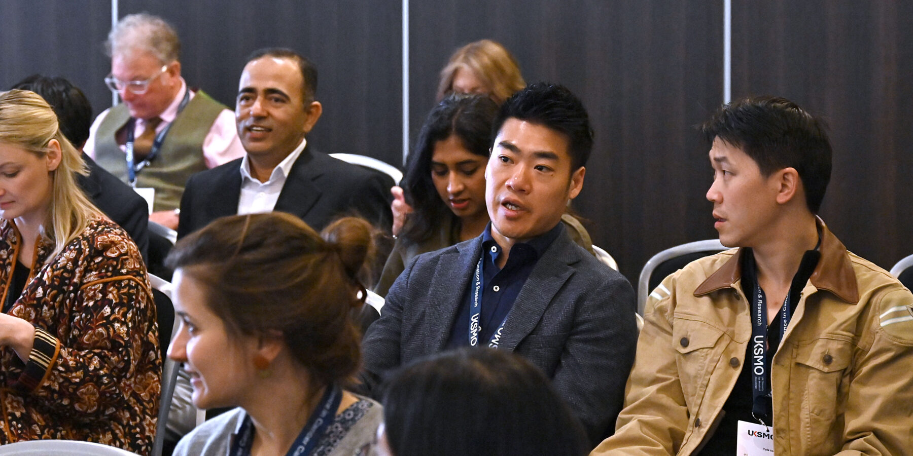 A close up of two members of an audience speaking to one another