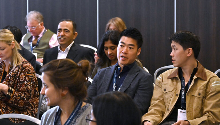 A close up of two members of an audience speaking to one another