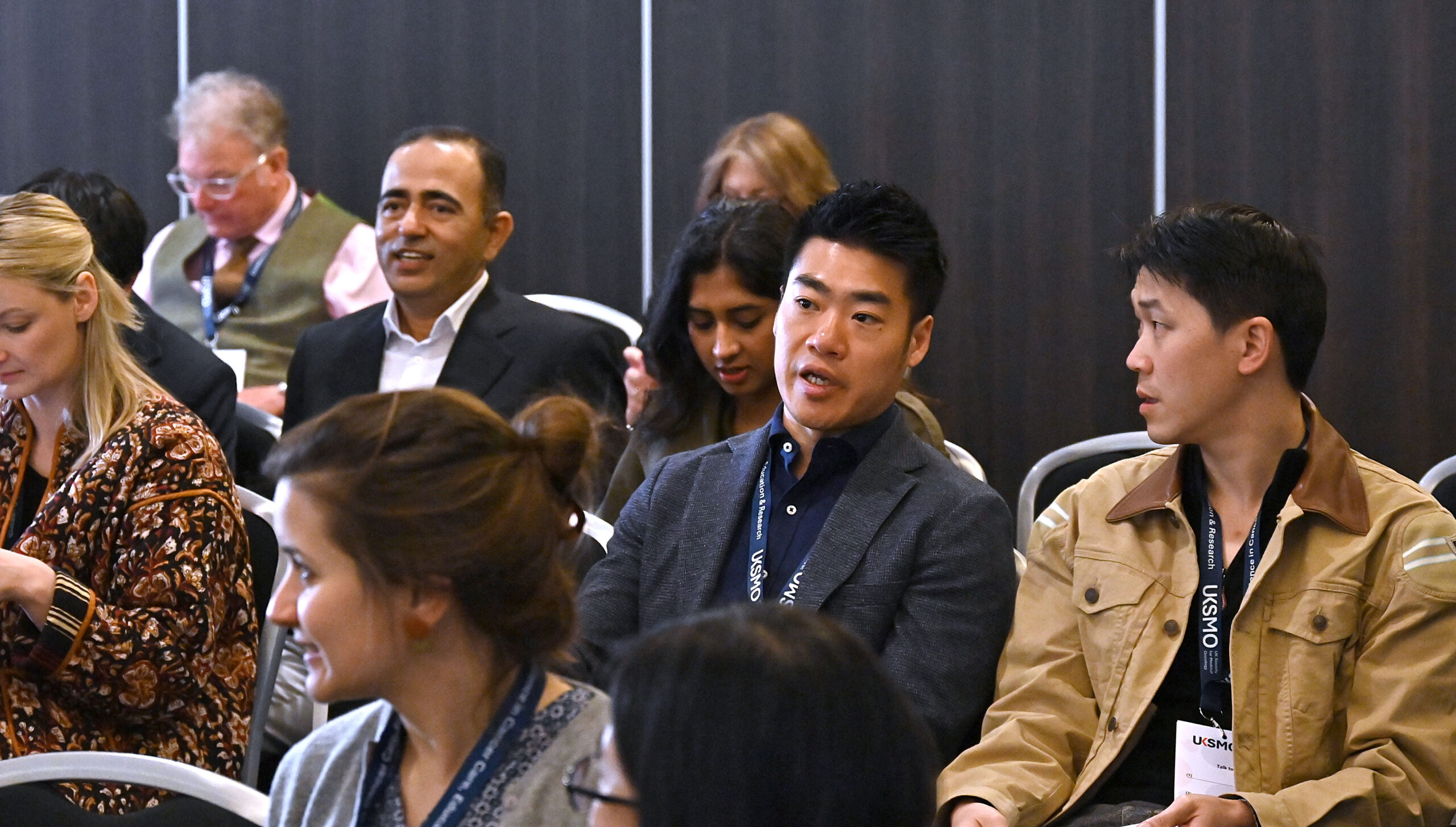 A close up of two members of an audience speaking to one another